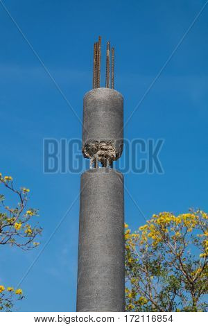 Construction method of connection on top of round concrete column with blue sky background.