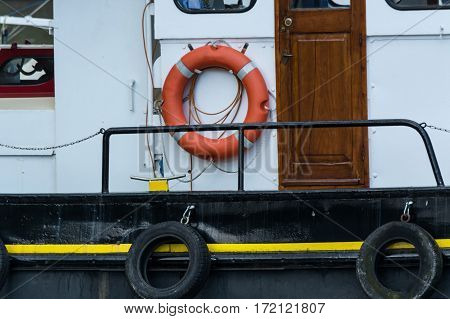 Side view of an old steel ship with lifebuoy in harbor.
