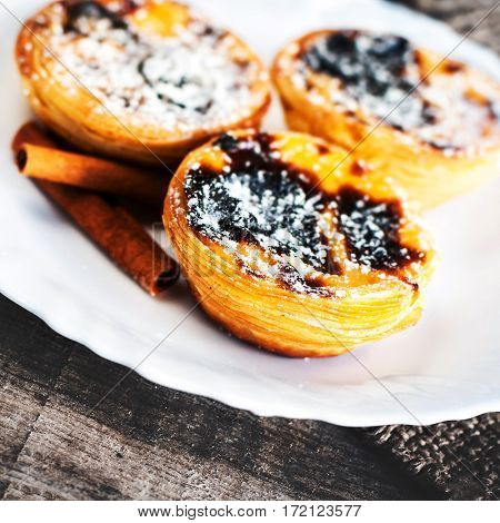 Egg tart - creamy sweet curstard on white plate on wooden table close up with copy space. Pasteis de Belem dessert