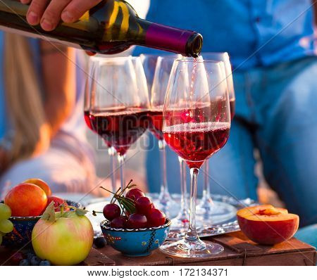 Group Of Happy Friends Having Red Wine On The Sunset Beach.