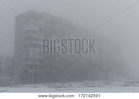 Foggy morning. Multi-storey building in the fog. Snowy morning and fog.