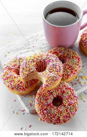 Iced doughnut rings with rainbow sparkl strands and cup of coffee, tea.