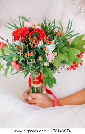 Beautiful woman in a white wedding dress holding a flowers bouquet in hand. Wedding bridal bouquet on a white background.