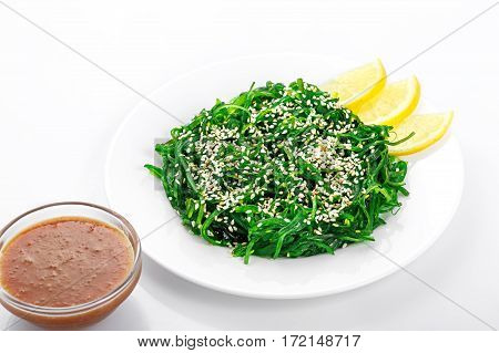 Salad Chuka, Chuka seaweed, walnut sauce , sesame seeds, on a white plate on a white background