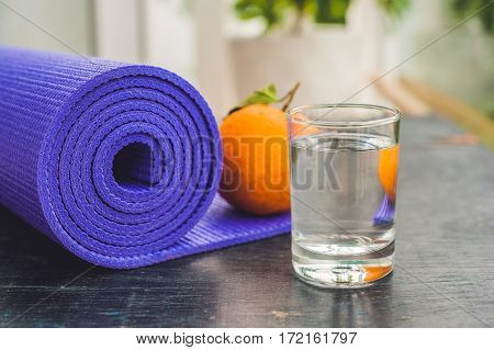 Yoga Mat, Water, Orange And Mango On A Wooden Background. Equipment For Yoga. Concept Healthy Lifest