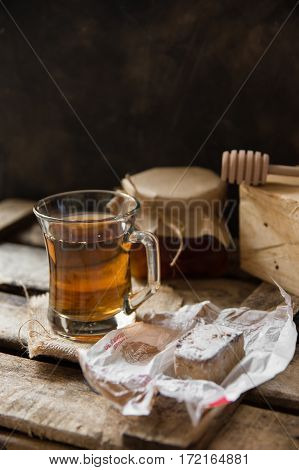 Cup of hot herbal tea jar with honey dipper Spanish christmas cookie polvoron on vintage wood box homeley cozy atmosphere selective focus