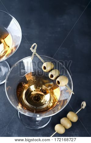 Martini glass and olives isolated on black concrete background