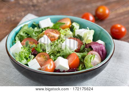 Salast with cherry tomatoes, Radicchio lettuce, frize, arugula and feta on wooden table