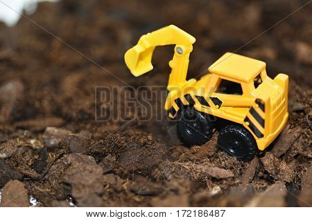 Small decorative excavator on ground. Macro abstract photo.