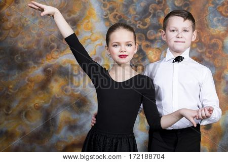 Young boy and girl are dancing on the studio wall background