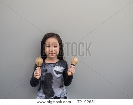 Little Asian Child Play The Maracas, Gray Background