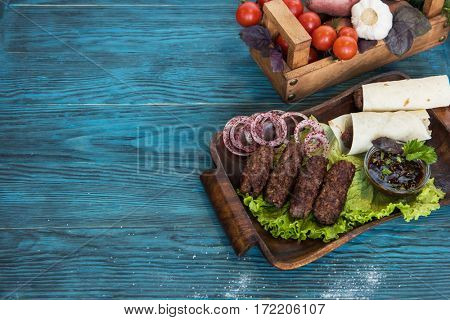 Grilled lula kebab - meat dish, with vegetable on a blue wooden background