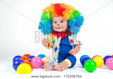 Children clown with a red nose multicolored wig in with balls. On a white background.