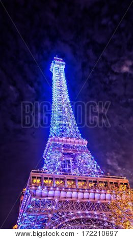 The replica eiffel tower at the parisan hotel on the island of macau lit up at night with lights in Asia.