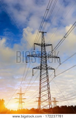 sunset with a silhouette of electricity pylon and power lines.