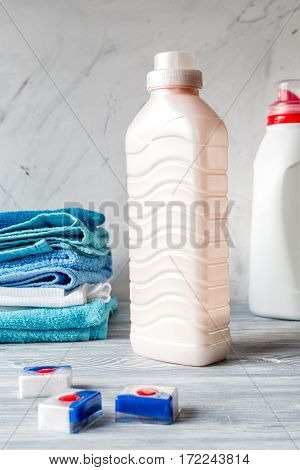 Pile of colorful clean towels with detergent on laundry gray background