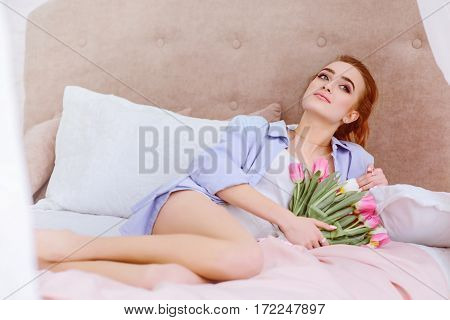attractive female resting on the bed in the light bedroom
