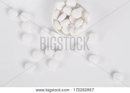 Round white pills and glass of water on a table waiting for eat