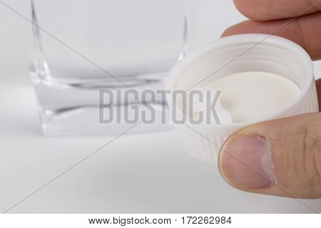 Round white pills and glass of water on a table waiting for eat