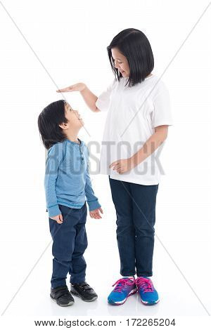 Asiangirl measures the growth of her brother on white background isolated