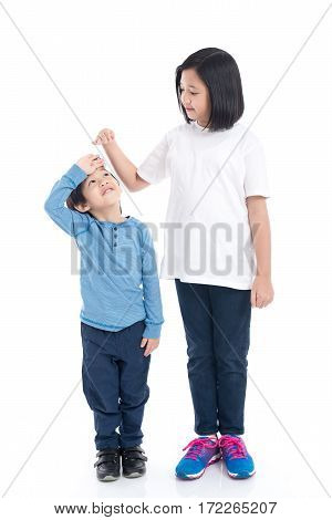 Asiangirl measures the growth of her brother on white background isolated