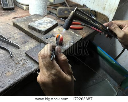 A gold making worker is firing on the gold ring to adjust its shape