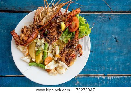 Tasty lobsters and jumbo prawns prepared with garlic and lime on tropical background