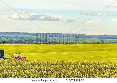 Small scale farming with tractor in field. Agricultural background.