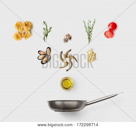 Cooking italian food, seafood pasta, isolated on white. Frutti di mare with fettuccine spaghetti. Mussels, prawn, shrimp, calamari rings and other ingredients over frying pan