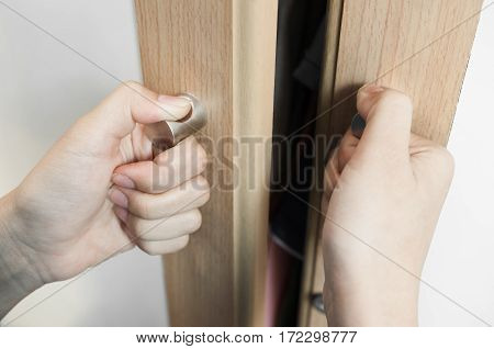 Closeup Hands of woman is holding on door handles of cabinet Door handles of closet or wardrobe