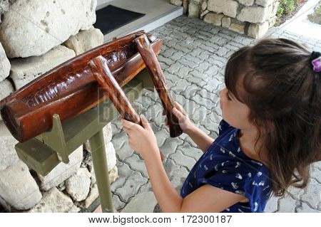 Child (girl age 6-7) play on a Fijian Lali stick drum in Nadi Viti leavu Island Fiji. Travel concept Real people copy space