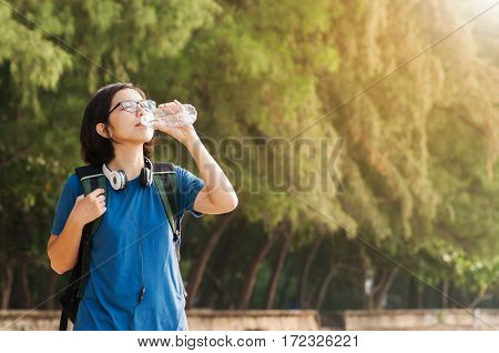 Asian woman traveller drinking water on nature background. copy space.