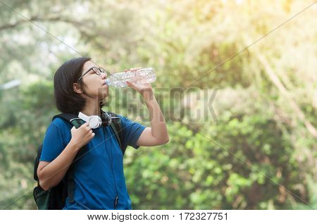 Asian woman hiker with backpack resting and drinking water with sunlight on nature background. copy space. Backpack.