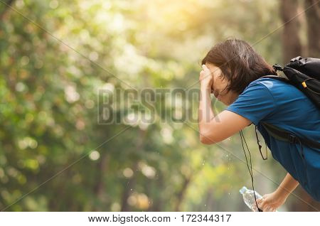 Close up Asian woman hiker pouring water from bottle on her face with nature background. copy space. Traveler.