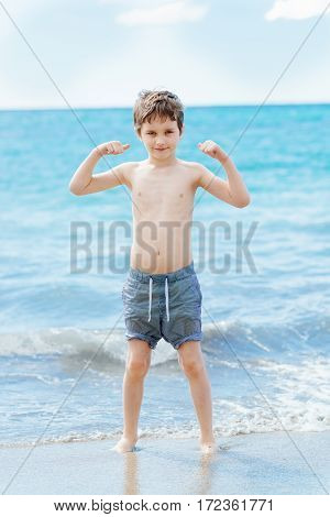 Happy 7 Years Boy In Victory Success Gesture On The Beach.