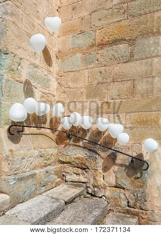 For a wedding is the entrance of a church in Largentiere in the Ardeche region of France decorated with white heart-shaped balloons