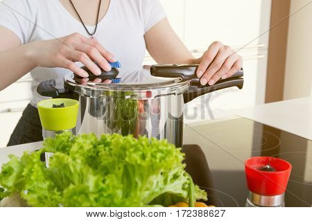 Woman uses pressure cooker to cook a meal. Conception of healthy nutrition.