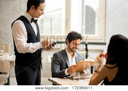 Cheerful couple with menu in a restaurant making order
