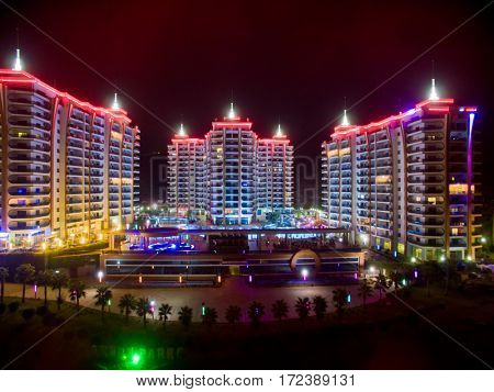 ALANYA, TURKEY - AUG 16, 2015: Three buildings of the residential complex Azura Park Residence with color light at night, aerial photo