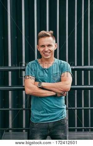 portrait of handsome man in a blue T-shirt outside building in summer