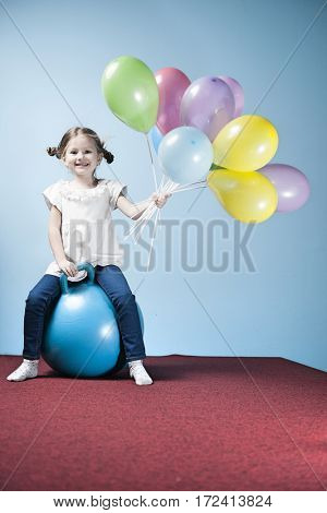 Young girl holding balloons on a hoppity horse