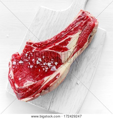 Fresh Raw Beef bone rib roughly choppid on white board with herbs.