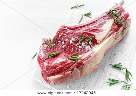 Fresh Raw Beef bone rib roughly choppid on white board with herbs.