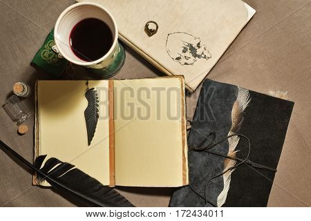 A mystical still life with old books, wineglass quill and charms