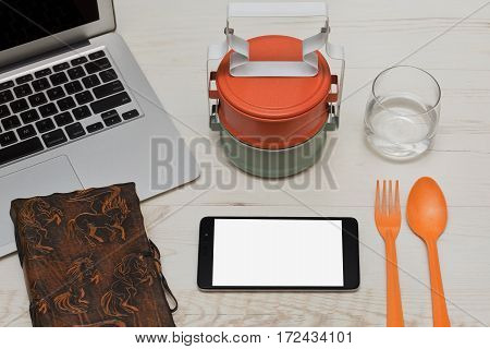 Everything is ready for the lunch on the workspace - asian styled food containers spoon and fork glass of still water and a cell phone for some internet browsing