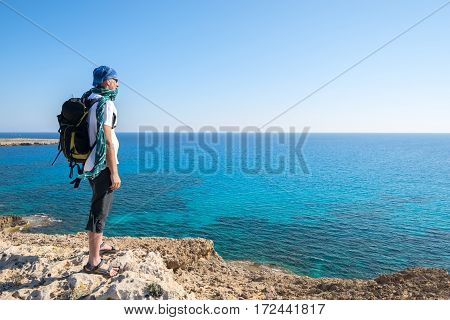 Traveler Bearded Man With Backpack Stands On A Rocky Seashore
