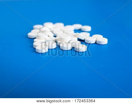 Many white pills on a blue background.