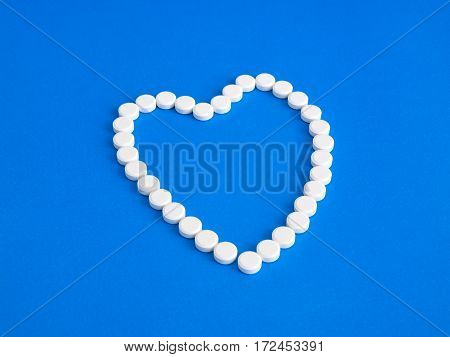 White pills on a blue background. Heart.