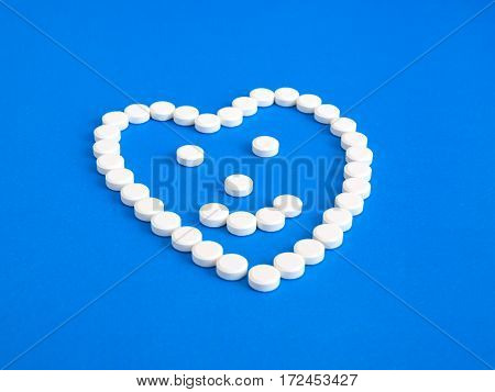White pills on a blue background. Heart and smile/