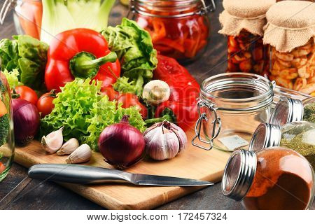 Jars With Marinated Food And Raw Vegetables On Cutting Board